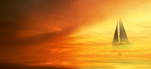 Sunset on the coast with a sailboat in the misty air